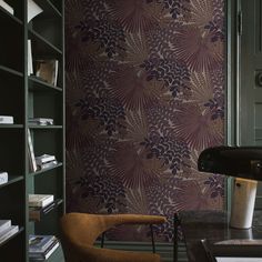 a room with a chair, bookshelf and wallpaper