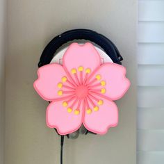 a pink flower attached to the side of a wall mounted hair dryer on a hook