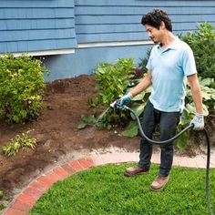 a man is using a garden hose to clean the grass