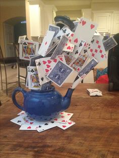 a blue teapot filled with playing cards on top of a wooden table