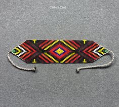 a red, yellow and green beaded tie on a gray background with the words crochet club written below it