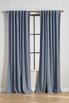 the curtains are hanging in front of a window with wood flooring and white walls