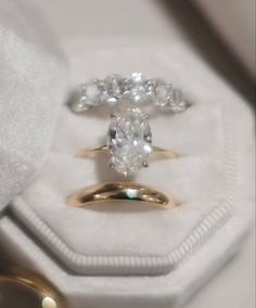 two wedding rings sitting on top of each other in a white ring box next to an engagement ring