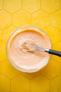 an overhead view of a bowl filled with mayonnaise and a whisk