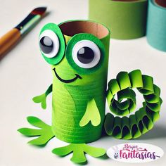 a roll of toilet paper with a green frog on it, next to some crafting supplies