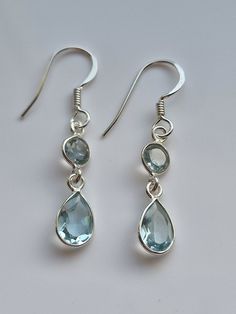 Behold the captivating allure of our blue topaz crystal earrings, a dazzling duo of celestial elegance. Crafted with meticulous precision, these earrings feature a perfect pairing of a lustrous round blue topaz crystal and a gracefully suspended teardrop-shaped blue topaz crystal, both delicately embraced by polished sterling silver settings. The round crystal, like a radiant full moon, enchants with its ethereal blue hue, while the teardrop crystal evokes a sense of timeless grace, shimmering w Blue Earrings Aesthetic, Blue Topaz Crystal, Ethereal Blue, Pretty Jewelry Necklaces, Topaz Crystal, Blue Crystal Earrings, Blue Dangle Earrings, Sagittarius Capricorn, Jeweled Earrings