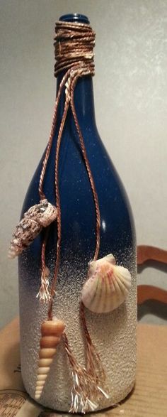 a blue bottle with seashells in it sitting on a table