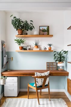 a wooden desk topped with lots of potted plants next to a wall mounted shelf