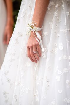 a close up of a person's hand wearing a wedding dress and holding a ring