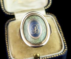 This beautiful antique Georgian era, late 18th century mourning ring is truly a beautifully crafted piece. It features a beautiful large oval face housing a lock of plaited dark blonde hair bordering a cobalt blue enamel plaque with applied rose gold lettering with the initial B. The slightly domed glazing encloses this and is original to the ring, the reverse of the face has a closed back setting and is engraved with an inscription for the departed; William Bridge, Ob 4th Mar 1797 Ae 81. The ring has chunky gold shoulders, yellow gold with warm rosey tones and a closed back setting.  It comes in an antique leather bound ring box.  A true beauty, this would be a fantastic gift for the collector of mourning jewellery or as a gift to yourself. Dated 18th century Georgian pieces are always in Antique Oval Ring With Initials, Antique Oval Rings With Initials, Heirloom Oval Engraved Enamel Ring, Antique Oval Initial Ring For Formal Occasions, Heirloom Engraved Oval Enamel Ring, Oval Yellow Gold Enamel Ring Engraved, Oval Yellow Gold Enamel Ring With Engraving, Engraved Oval Enamel Ring In Yellow Gold, Oval Engraved Yellow Gold Enamel Ring