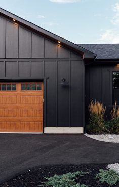 a black house with two brown garage doors