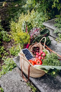 a basket filled with lots of different types of fruits and vegetables sitting on top of cement steps