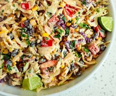 a white bowl filled with pasta salad and garnished with limes