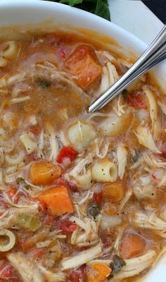 a bowl of soup with noodles and carrots on the side next to some parsley