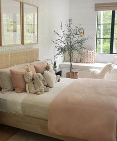 a bed with pillows and stuffed animals on it in a room that has white walls