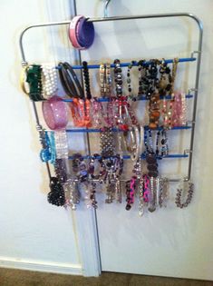 a rack with bracelets and other jewelry hanging from it's sides in front of a door