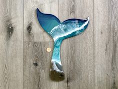 a blue glass whale tail sitting on top of a wooden floor