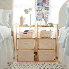 two baskets are stacked on top of each other in front of a bed with white sheets and pillows