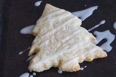 a cookie with icing sitting on top of a black surface next to white liquid