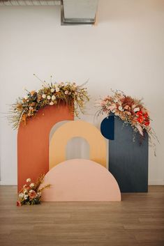 three different colored vases with flowers in them on the floor next to each other