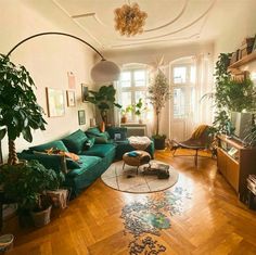 a living room filled with furniture and lots of plants on top of hard wood flooring