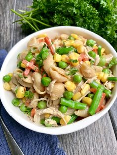 a white bowl filled with pasta and veggies on top of a wooden table