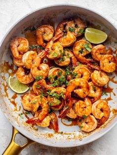 a skillet filled with cooked shrimp and garnished with cilantro sauce