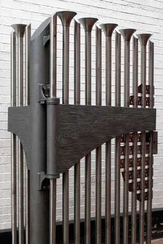 an iron gate with wooden slats in front of a white brick wall and floor