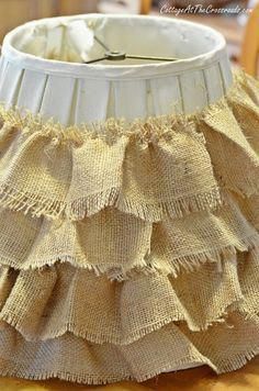 a white lamp shade with ruffles on it sitting on top of a wooden table