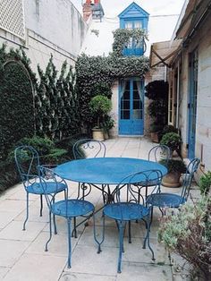 an outdoor table and chairs in the middle of a courtyard with potted plants on either side