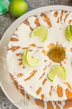 a cake with white icing and limes on top, sitting on a plate