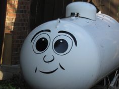 a large white tank with a face drawn on it's side in front of a brick building