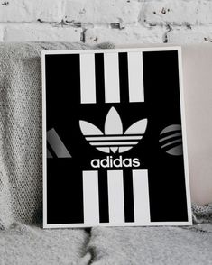 a black and white adidas poster sitting on top of a couch next to a pillow