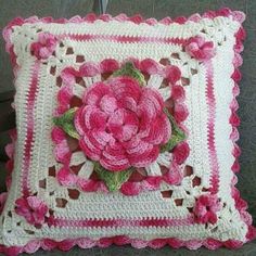 a crocheted pillow with pink flowers on it