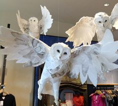 an owl sculpture hanging from the ceiling in a store