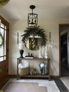 the entryway is decorated for christmas with wreaths and pine cones on the table