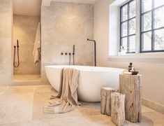 a bathroom with a large bathtub and wooden stumps on the floor next to it