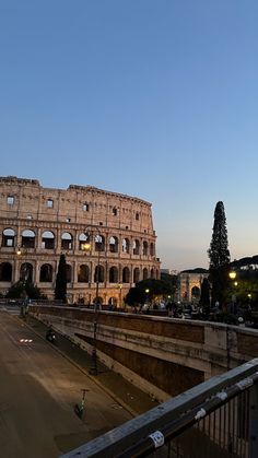 the colossion in rome at dusk with people walking on the street below it