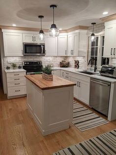 a kitchen with white cabinets and wooden counter tops, an island in between the stove and refrigerator