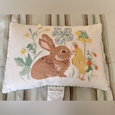 a pillow with an image of a rabbit and chick on it's side, sitting on a bed