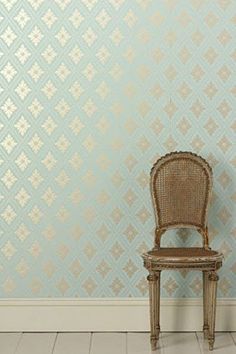 a chair sitting in front of a wall with a pattern on it