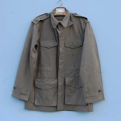 This listing is for a medium/large Khaki French army jacket, as new, in pure cotton fabric. Think this is an M47 Jacket from the Indochina conflicts, made in 1954 and then packed away without seeing any action.  It is very nicely made by Paul Boyé.  It has button fastenings, 4 outside pockets, two inside pockets and with a drawstring waist.  Not sure of the size but suitable for a 38/40 inch chest . A recent brocante find here in France, belonged to a Paratrooper it seems. Sizes are approximate and variable, serve as a guide only.  Please check the following dimensions carefully before purchasing The front measures 53cm/ 21 inches from underarm-underarm when laid flat From shoulder to shoulder straight across the front is 46cm/ 18 inches  The length at the back from nape to hem is 77 cm/ 3 Combat Style Khaki Cotton Utility Jacket, Khaki Cotton Combat Utility Jacket, Olive Cotton Military Style Utility Jacket, Olive Military Cotton Utility Jacket, Olive Cotton Military Utility Jacket, Vintage Khaki Parka With Flap Pockets, Military Style Cotton Parka With Flap Pockets, Vintage Cotton Parka, French Army