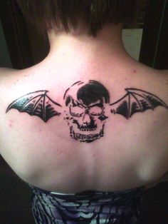 a woman with a skull and bat tattoo on her back