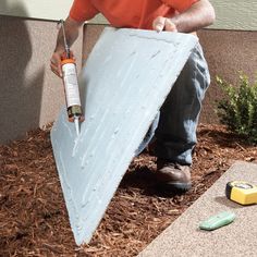 a man is painting the side of a house with paint and wood shavings