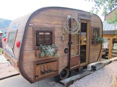 an old trailer is parked on the side of the road with plants growing out of it