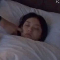 a woman laying in bed with her eyes closed