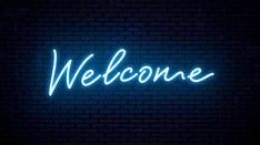 a neon welcome sign on a brick wall with the word'welcome'lit up