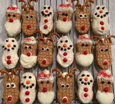 christmas cookies decorated to look like reindeers and snowmen are on a cooling rack