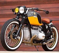 a yellow and black motorcycle parked in front of a wooden garage door with its lights on