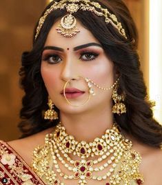 a woman wearing an elaborate necklace and nose ring with pearls on her head, in gold jewelry